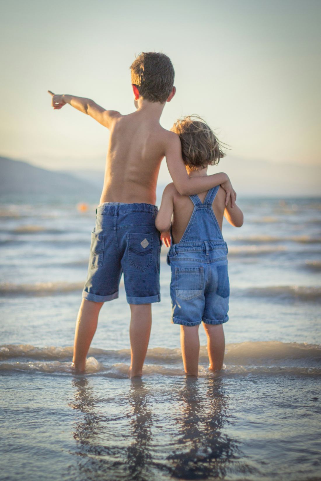 Zwei Kinder am Strand blicken aufs Meer