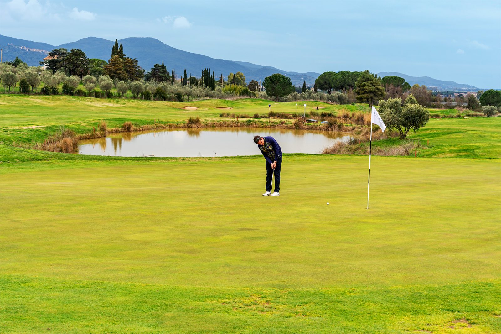 Golfer putting on the green at Golf Club Toscana